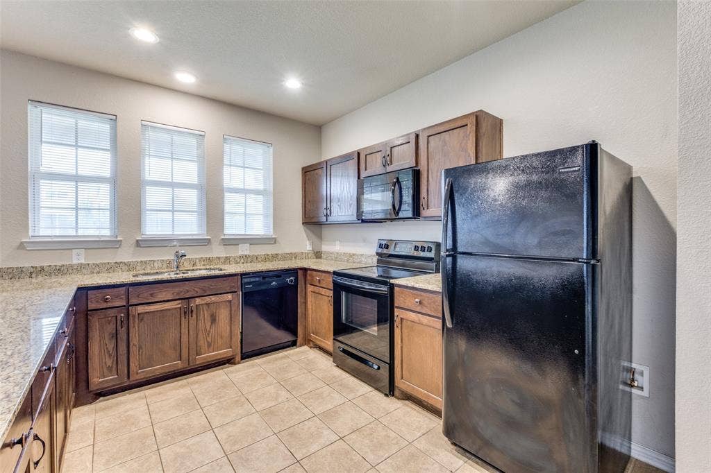 4662 Ralph Lane, Dallas, TX 75227 Kitchen featuring wooden cabinetry, stone-surface countertops, tile flooring, recessed lighting, and black appliances