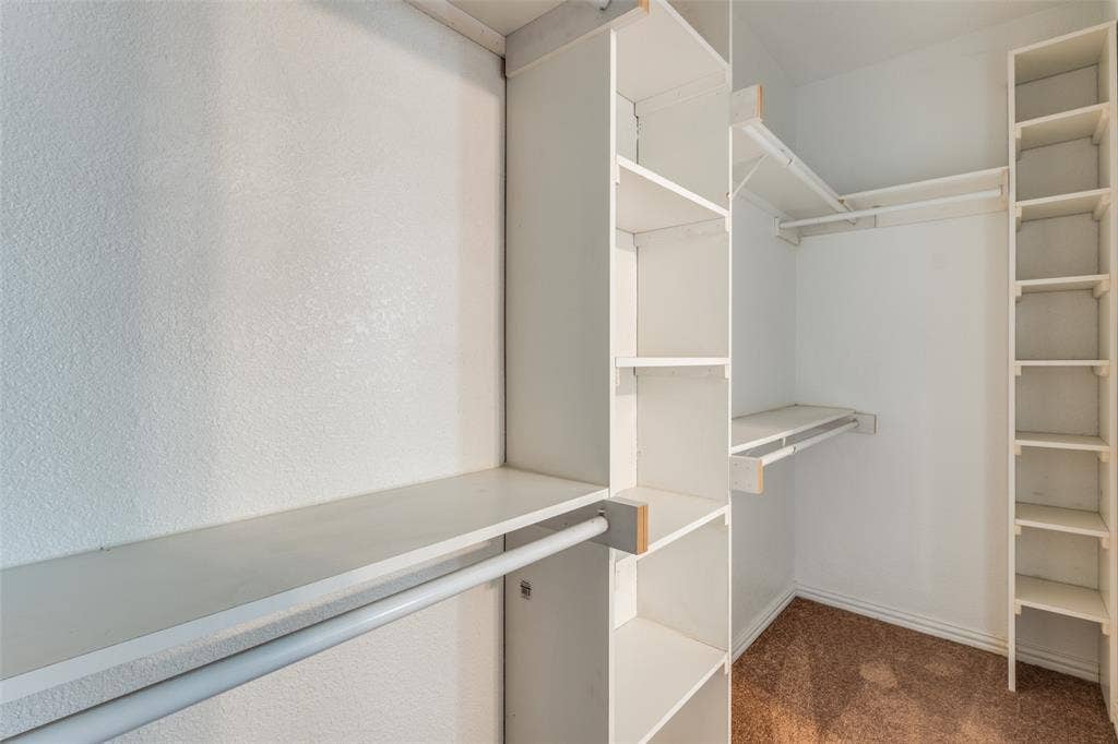 4662 Ralph Lane, Dallas, TX 75227 Walk-in closet featuring white built-in shelving towers, dual-level hanging rods, and carpeting