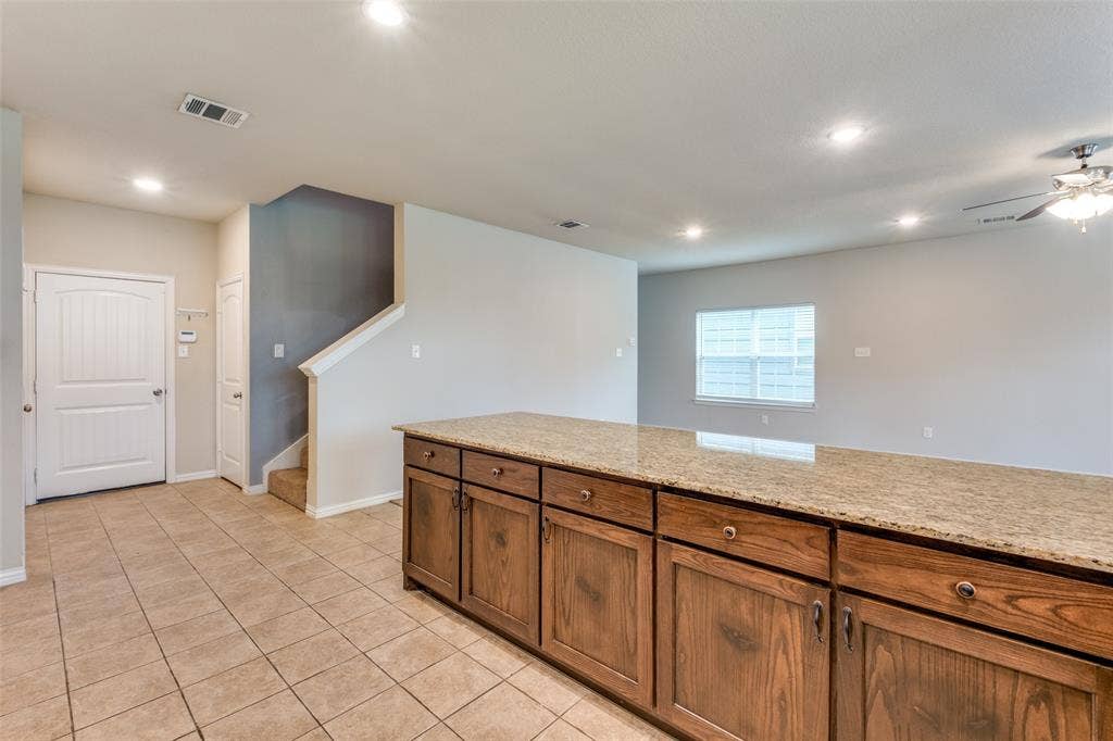 4662 Ralph Lane, Dallas, TX 75227 Kitchen island with stone countertop and wood-finish cabinetry, tile flooring, recessed lighting, and ceiling fan