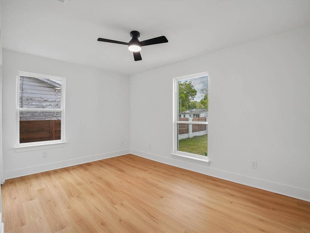9059 Quinn Street, Dallas, TX 75217 Room featuring wood-finish flooring, white walls, dual windows, and a matte black ceiling fan with integrated lighting