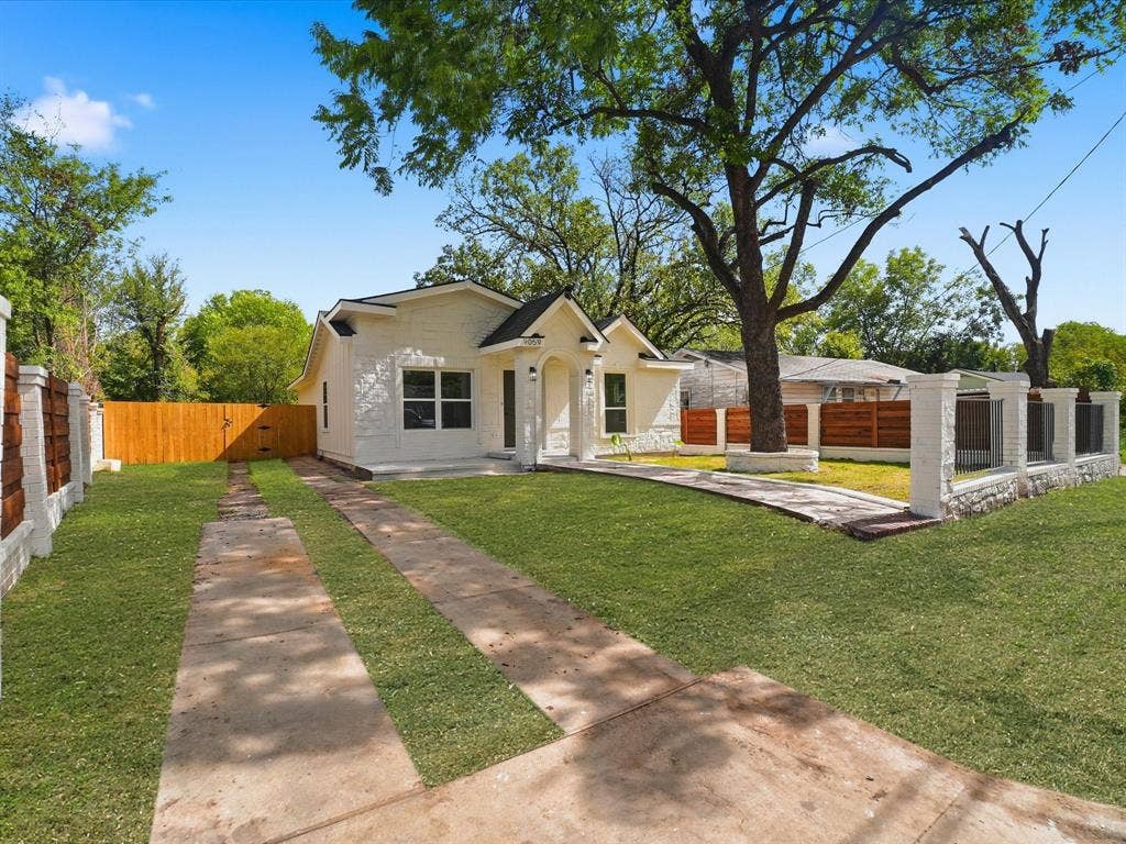 9059 Quinn Street, Dallas, TX 75217 Single-story residence featuring a painted masonry exterior, covered front entryway, concrete ribbon driveway, and perimeter wood privacy fencing with masonry pillar accents
