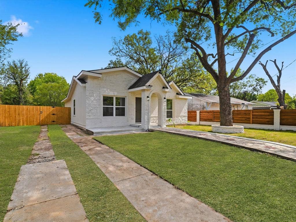 9059 Quinn Street, Dallas, TX 75217 Exterior featuring a textured stone facade, a covered entryway with an arched portico, and wood-finish horizontal privacy fencing