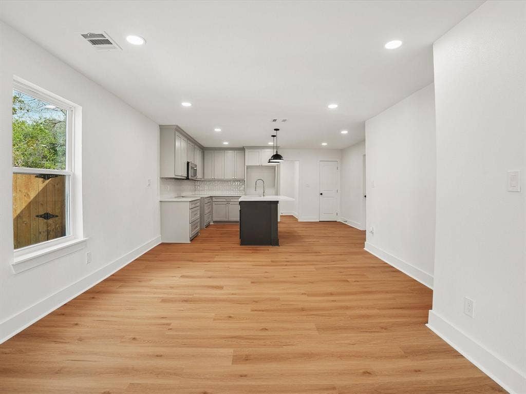 9059 Quinn Street, Dallas, TX 75217 Open-concept kitchen featuring light-toned cabinetry, a dark-toned central island, recessed lighting, and wood-finish flooring
