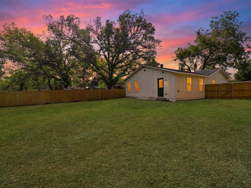 9059 Quinn Street, Dallas, TX 75217 Expansive backyard featuring a level lawn, mature trees, and a full wood-fence perimeter