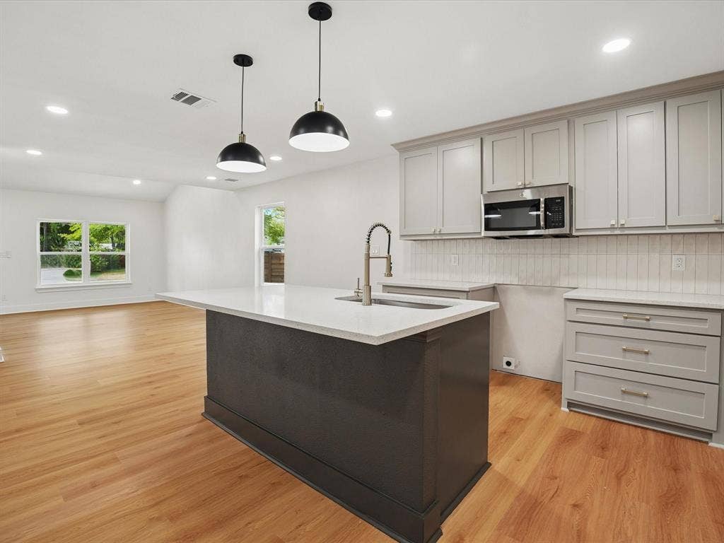 9059 Quinn Street, Dallas, TX 75217 Kitchen featuring a center island with a stone-finish countertop, shaker-style cabinetry, recessed lighting, dual pendant light fixtures, and wood-finish flooring