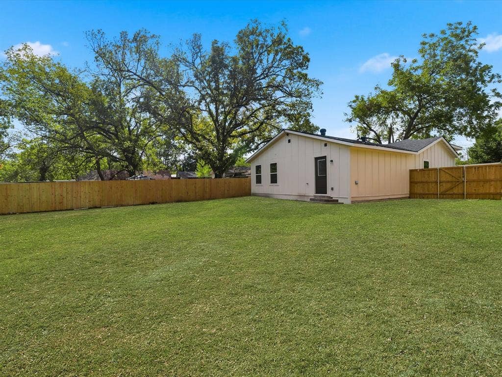 9059 Quinn Street, Dallas, TX 75217 Expansive backyard featuring a manicured lawn, wood-panel fencing, and mature trees
