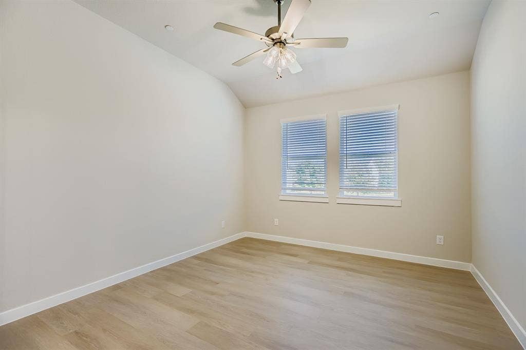 1204 Pebblebrook Drive, McKinney, TX 75071 Room with vaulted ceiling, neutral wall tones, wood-finish flooring, dual windows with blinds, and a central ceiling fan with integrated light fixture