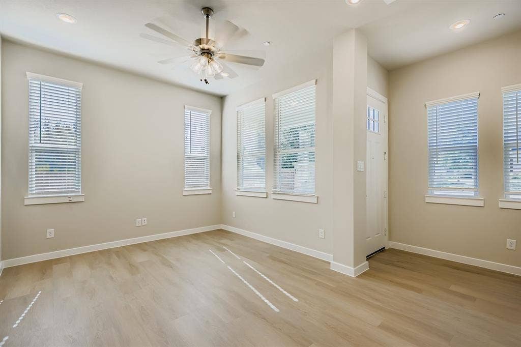 1204 Pebblebrook Drive, McKinney, TX 75071 Neutral-toned interior featuring wood-finish flooring, recessed lighting, a brushed-nickel ceiling fan, and multiple windows with horizontal blinds
