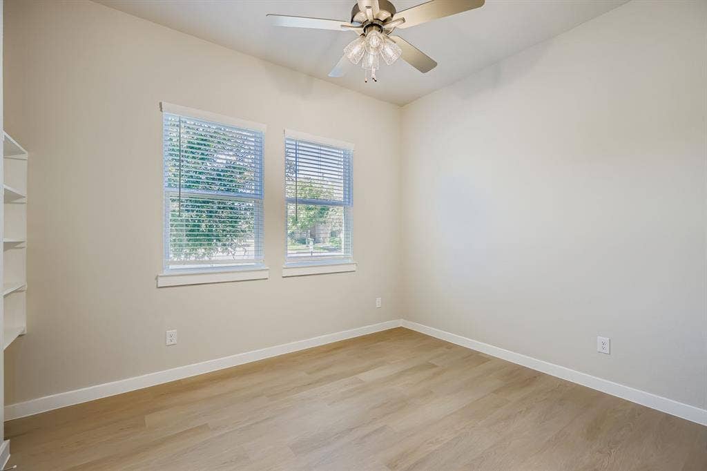 1204 Pebblebrook Drive, McKinney, TX 75071 Room featuring wood-finish flooring, dual windows with blinds, built-in shelving, and a multi-light ceiling fan