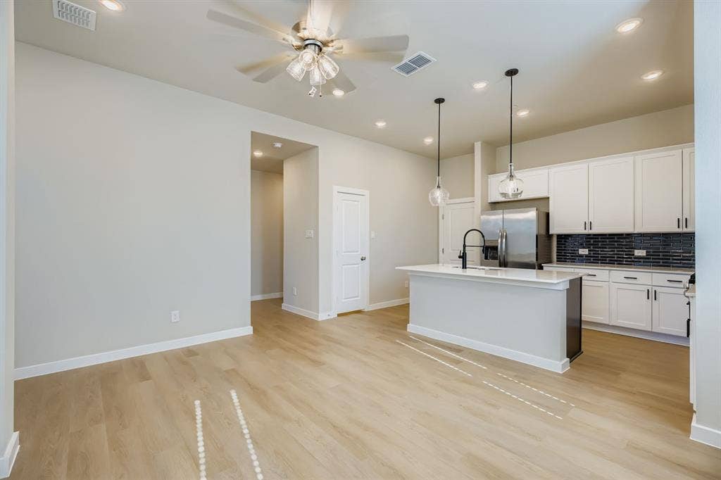 1204 Pebblebrook Drive, McKinney, TX 75071 Kitchen featuring white shaker-style cabinetry, quartz countertops, a black tile backsplash, stainless steel appliances, and wood-finish flooring