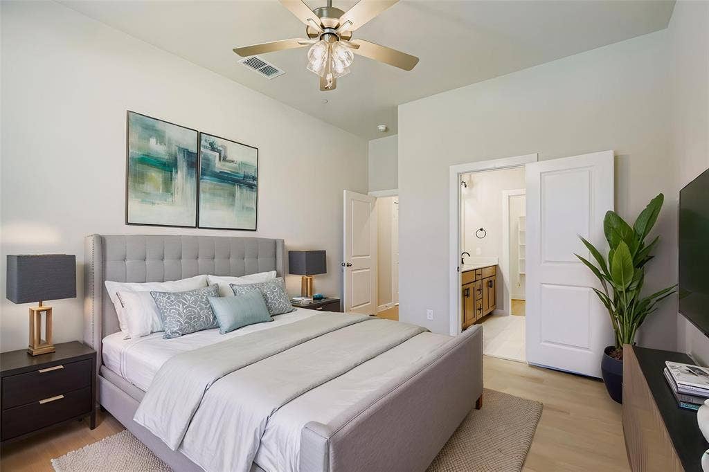 1204 Pebblebrook Drive, McKinney, TX 75071 High-ceiling bedroom featuring wood-finish flooring, a central multi-blade ceiling fan with integrated light fixture, and two-panel interior doors
