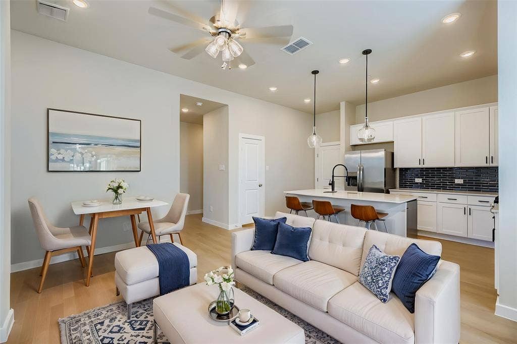 1204 Pebblebrook Drive, McKinney, TX 75071 Open-concept living space featuring wood-finish flooring, recessed lighting, and a kitchen equipped with white cabinetry, a center island with a stone countertop, and a dark tiled backsplash