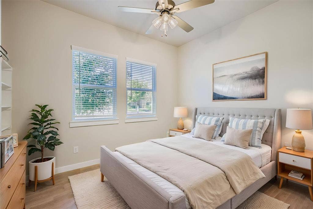 1204 Pebblebrook Drive, McKinney, TX 75071 High-ceiling room featuring neutral wall tones, wood-finish flooring, dual windows with horizontal blinds, and a multi-light ceiling fan