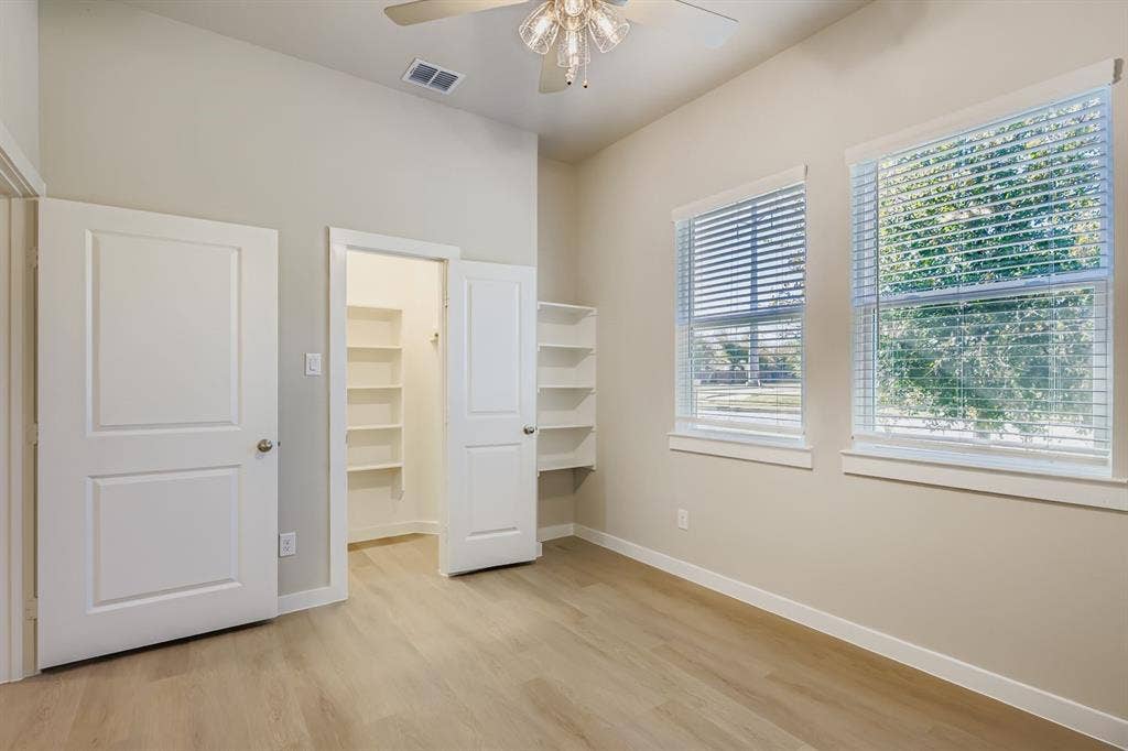 1204 Pebblebrook Drive, McKinney, TX 75071 Room featuring high ceilings, wood-finish flooring, dual windows with blinds, and built-in shelving