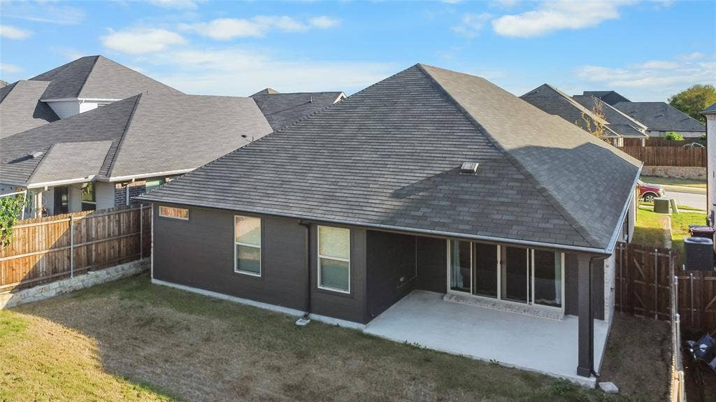 614 Martell Road, Lowry Crossing, TX 75069 Rear elevation featuring a covered concrete patio, dark-toned exterior siding, a shingled roof, and perimeter wood fencing