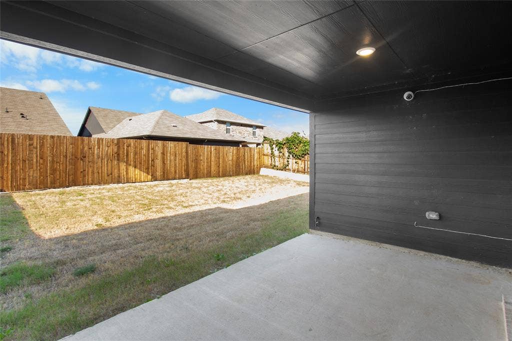 614 Martell Road, Lowry Crossing, TX 75069 Covered concrete patio featuring dark horizontal siding, recessed lighting, and an enclosed backyard with wood privacy fencing