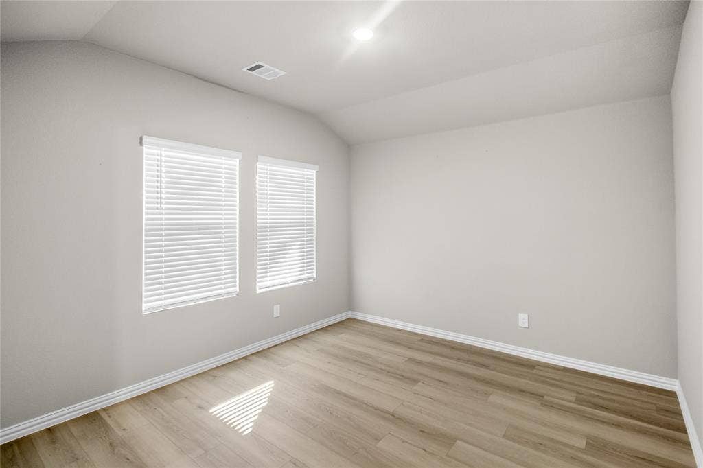 614 Martell Road, Lowry Crossing, TX 75069 Vaulted ceiling featuring neutral wall paint, wood-finish flooring, and dual windows with fitted blinds