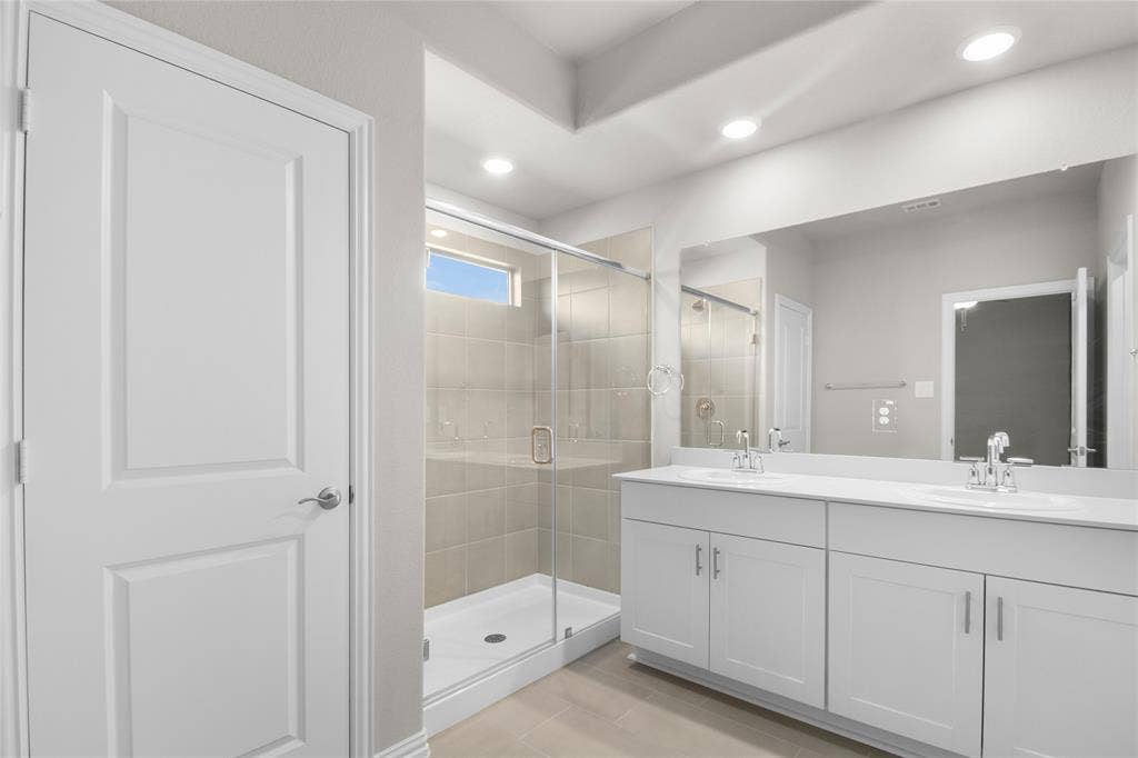 614 Martell Road, Lowry Crossing, TX 75069 Double vanity with white cabinetry, solid-surface countertops, dual undermount sinks, frameless glass-enclosed shower with tiled walls, and recessed lighting