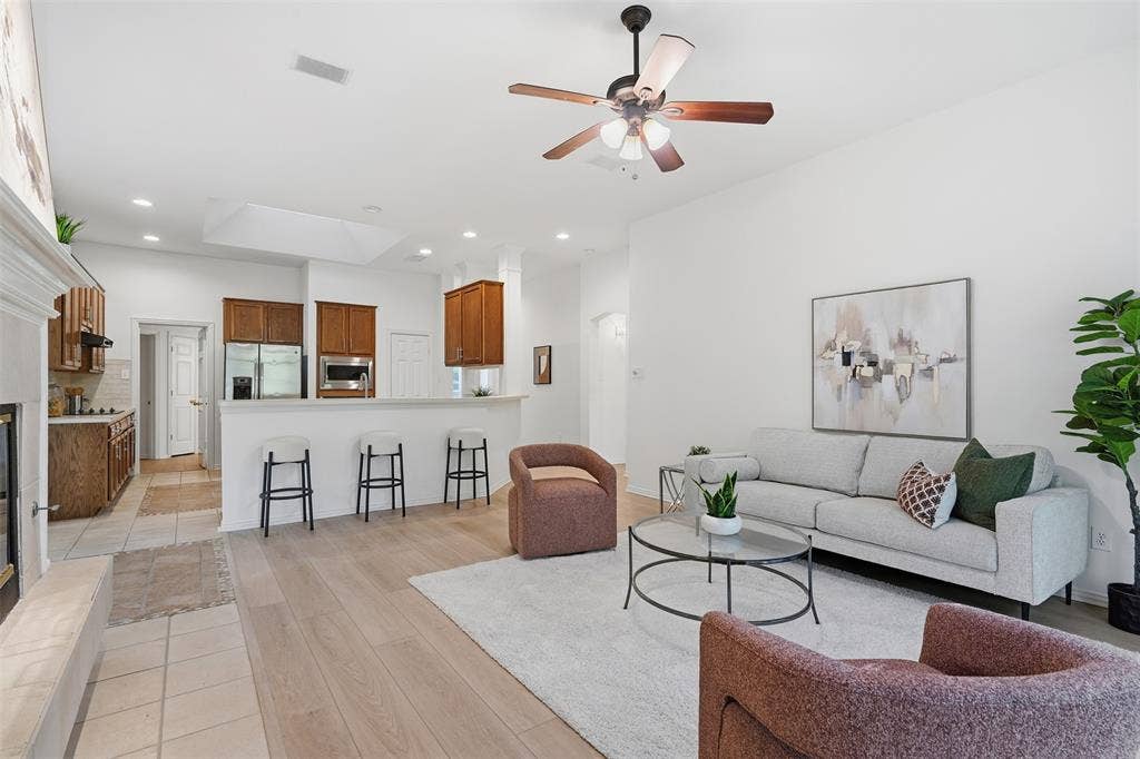 2902 Glen Hollow Court, McKinney, TX 75072 Open-concept living space featuring wood-finish flooring, a neutral color palette, recessed lighting, a ceiling fan with integrated light fixture, and a kitchen breakfast bar