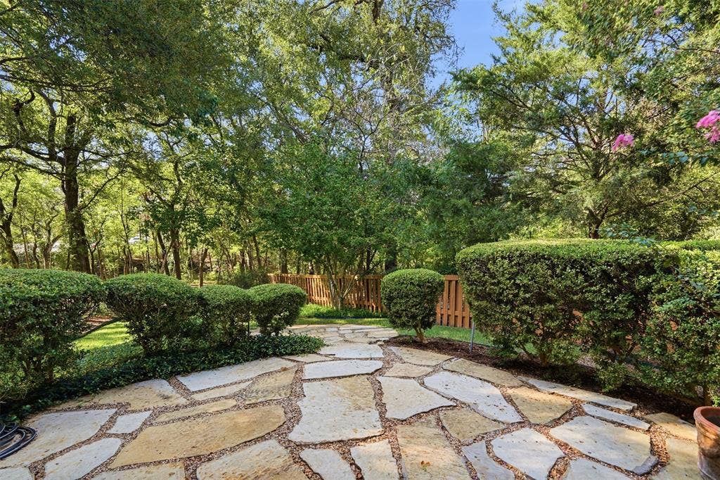 2902 Glen Hollow Court, McKinney, TX 75072 Flagstone patio featuring manicured hedges, mature tree canopy, and wood privacy fencing