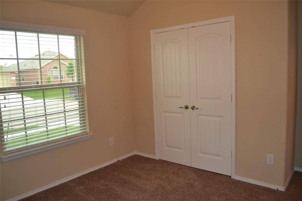 Interior space featuring vaulted ceilings, double-panel closet doors with satin nickel hardware, and a single-pane window with horizontal blinds