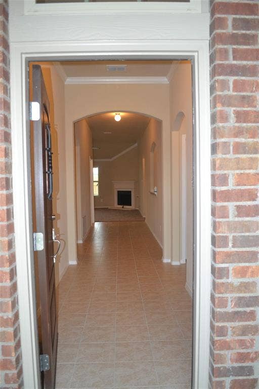 Entryway featuring red brick exterior trim, tile flooring, arched ceiling detailing, and a decorative inset fireplace