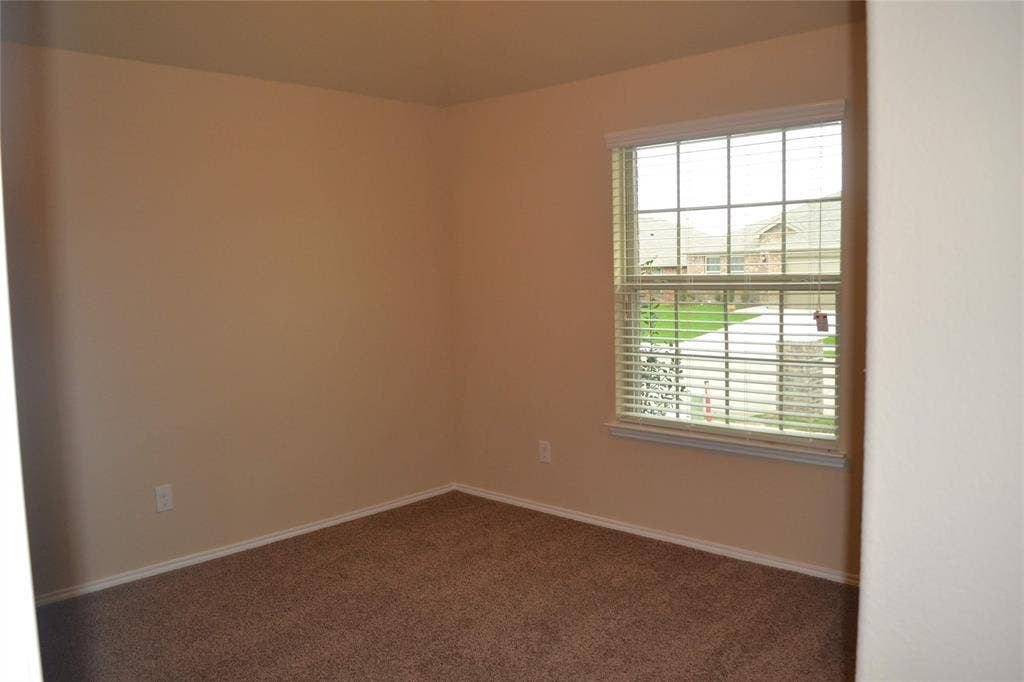 Neutral wall palette, wall-to-wall carpeting, and a double-pane window featuring a grid pattern and fitted blinds