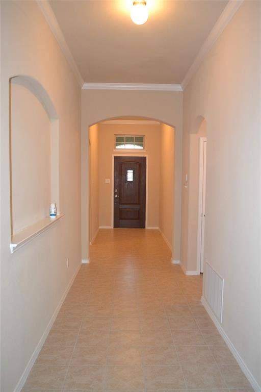 Entryway featuring tile flooring, crown molding, an arched architectural wall niche, and an exterior door with a transom window