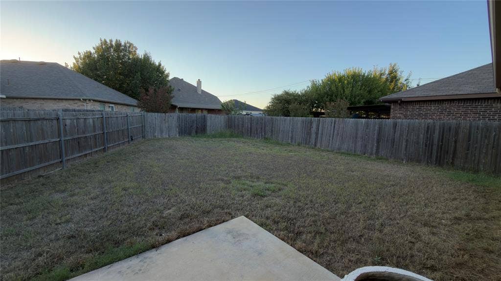 8808 Irish Bend Drive, Fort Worth, TX 76123 Backyard featuring a concrete patio, wood privacy fencing, and open lawn space