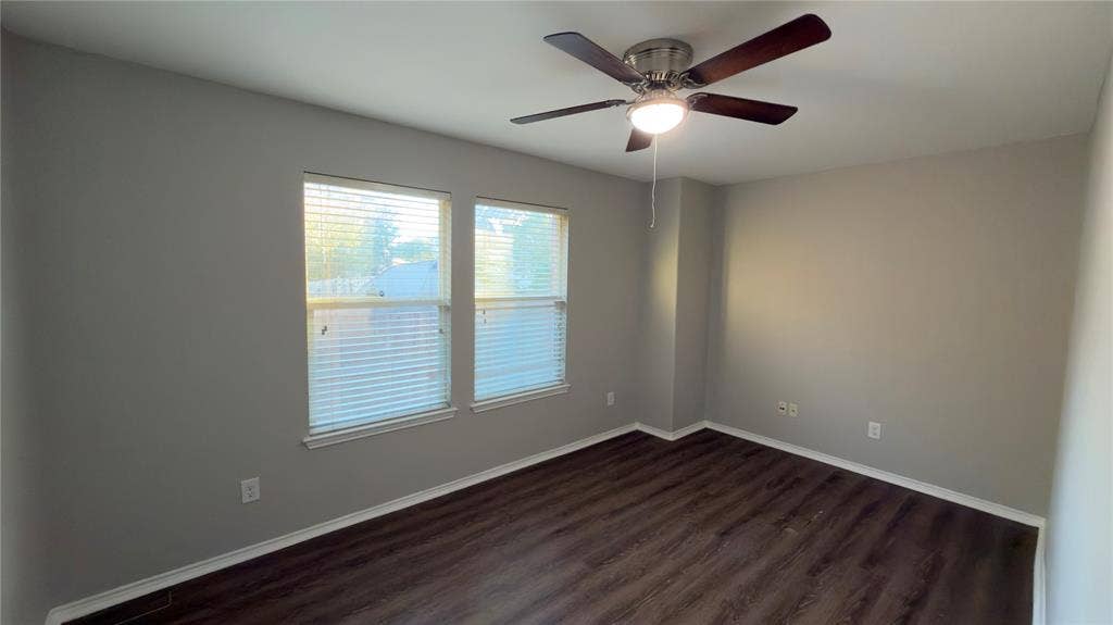 8808 Irish Bend Drive, Fort Worth, TX 76123 Neutral-toned interior featuring wood-finish flooring, dual windows with blinds, and a central ceiling fan with an integrated light fixture
