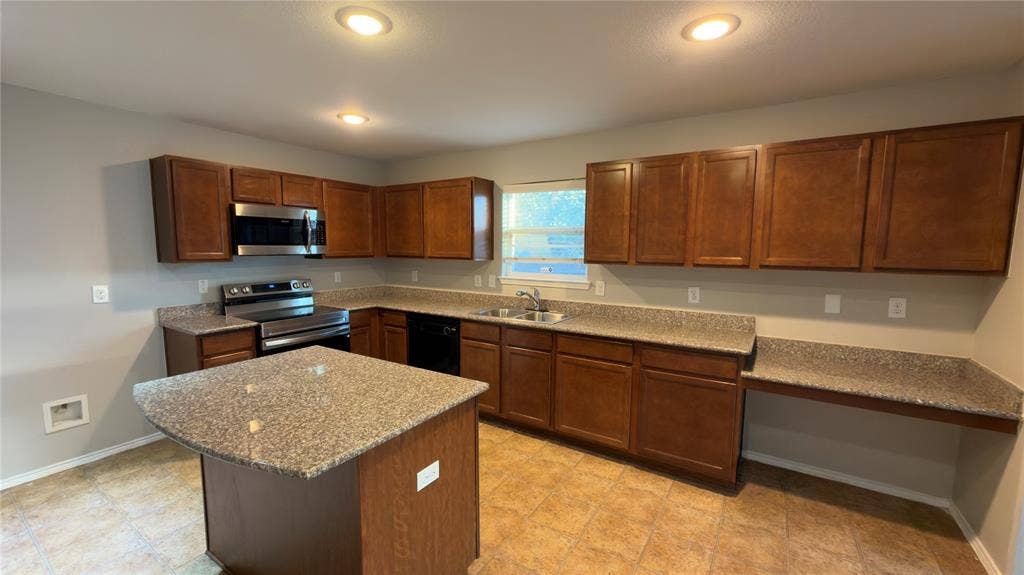 8808 Irish Bend Drive, Fort Worth, TX 76123 Kitchen featuring wood cabinetry, stone-finish countertops, a central island, integrated stainless steel appliances, and recessed ceiling lighting