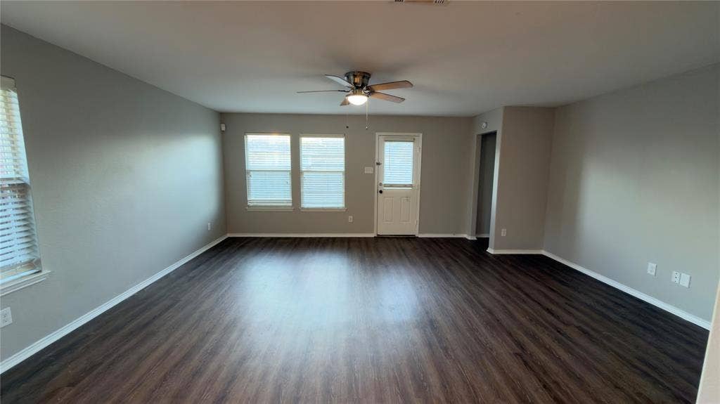 8808 Irish Bend Drive, Fort Worth, TX 76123 Open interior space featuring wood-finish flooring, neutral wall paint, a ceiling fan with integrated light fixture, and multiple windows with horizontal blinds