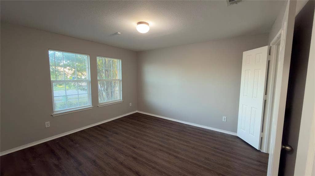 8808 Irish Bend Drive, Fort Worth, TX 76123 Room featuring wood-finish flooring, neutral wall paint, two dual-pane windows with muntins, and a six-panel interior door