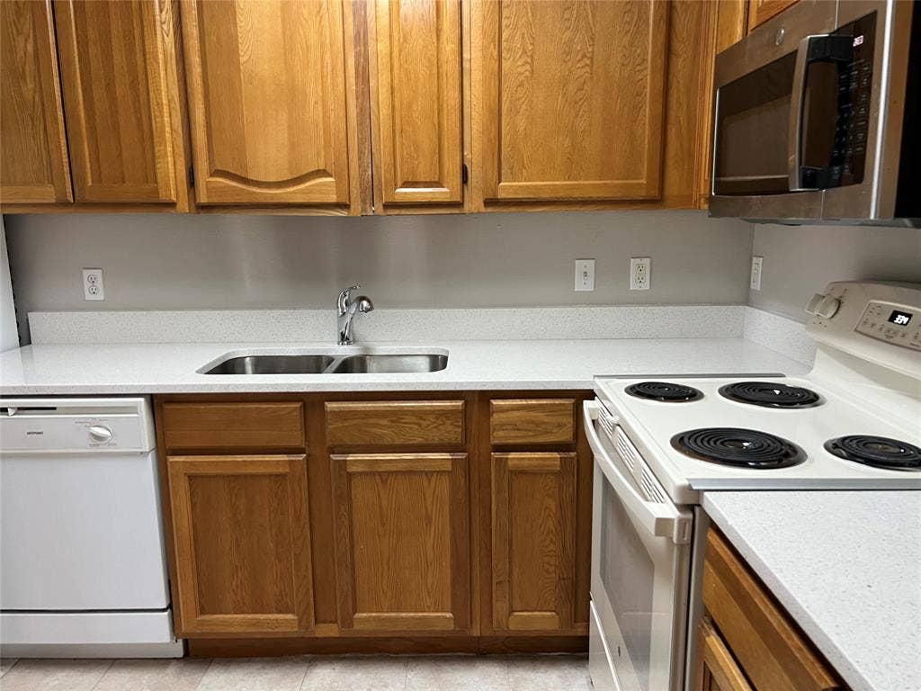 Kitchen with white appliances, sink, and light tile floors