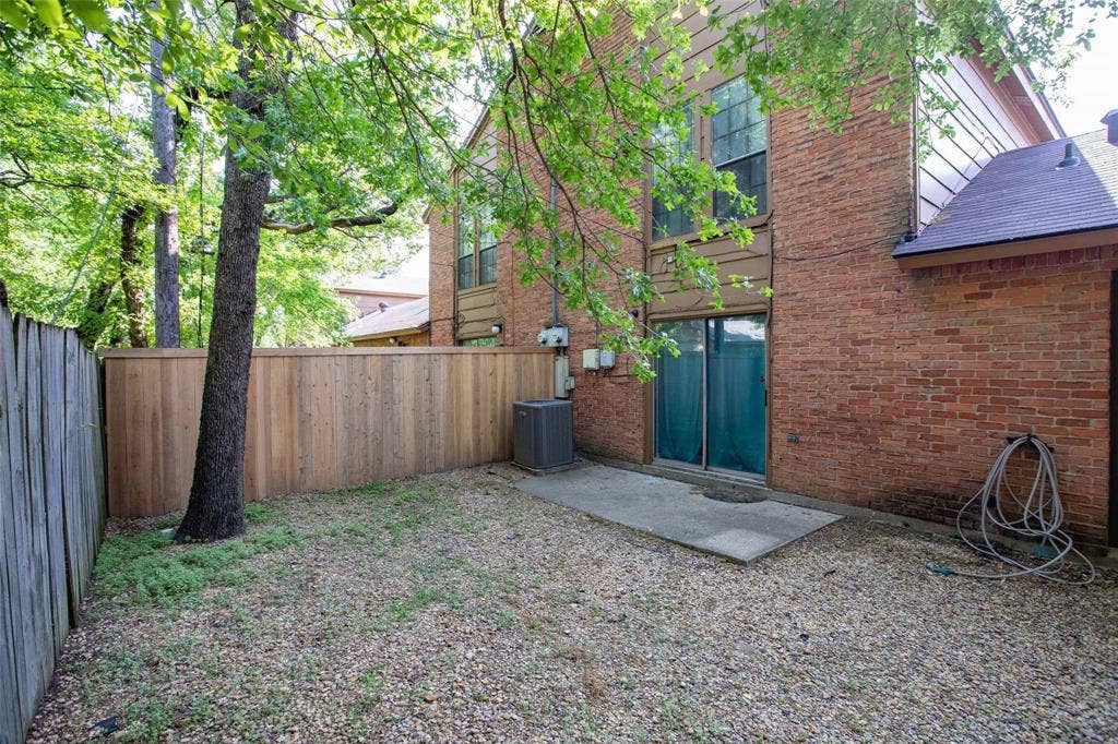 Brick exterior with sliding glass doors, concrete patio, and a wood privacy fence