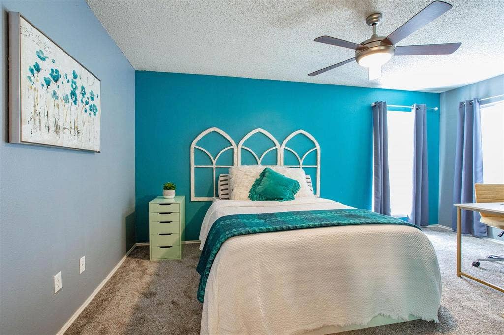 Neutral-toned carpeting, ceiling-mounted light fixture with fan, and windows with integrated hardware