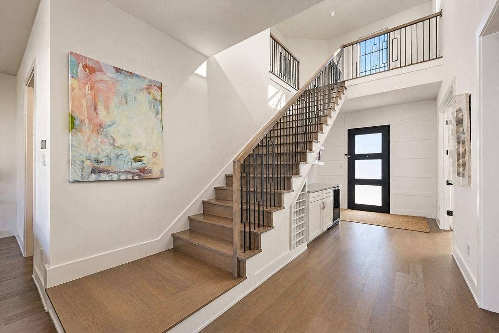4515 Cowan Avenue, Dallas, TX 75209 Hardwood floors sweep past the open staircase and custom dry bar, setting an inviting tone the moment you walk through the door