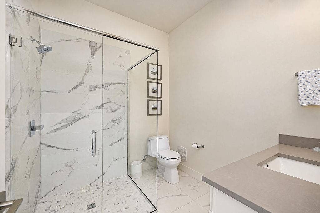 4515 Cowan Avenue, Dallas, TX 75209 A full main-floor bathroom with a frameless glass shower and quartz vanity gives downstairs guests complete privacy