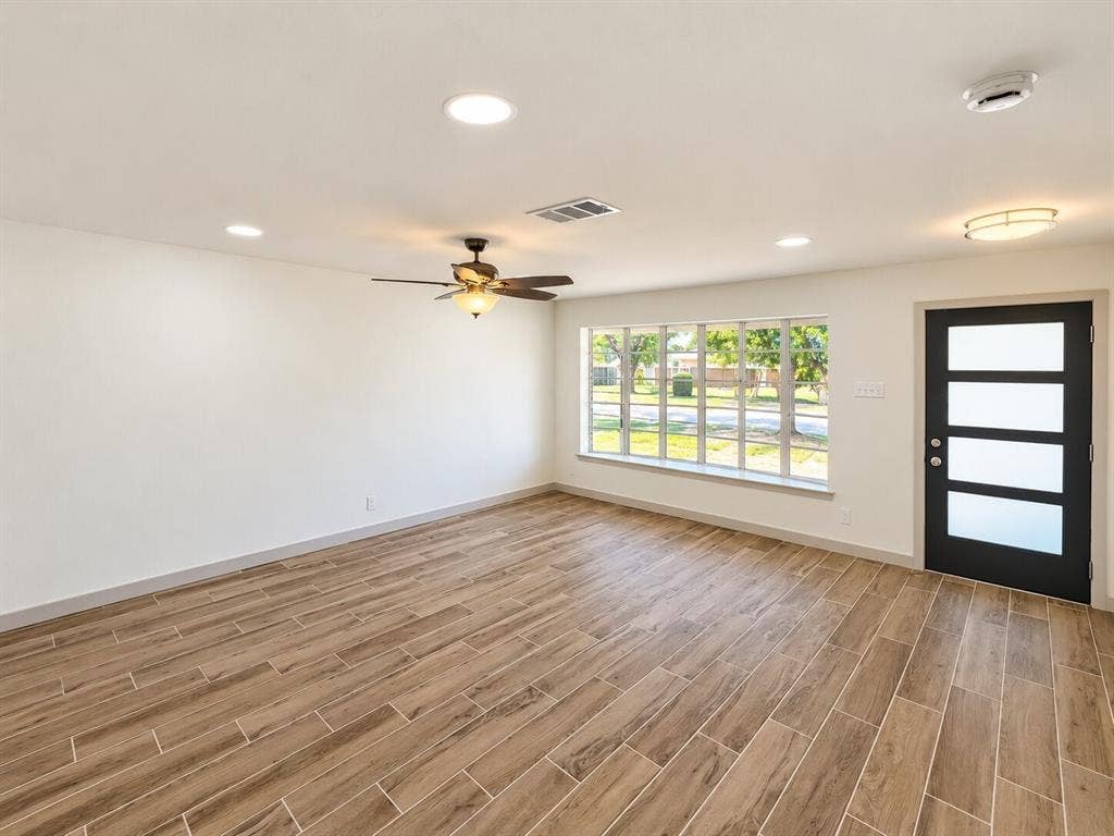 2551 Pinebluff Drive, Dallas, TX 75228 Wood-finish flooring, recessed lighting, ceiling fan with light kit, expansive window with grid panes, and a modern entry door featuring four frosted glass panels