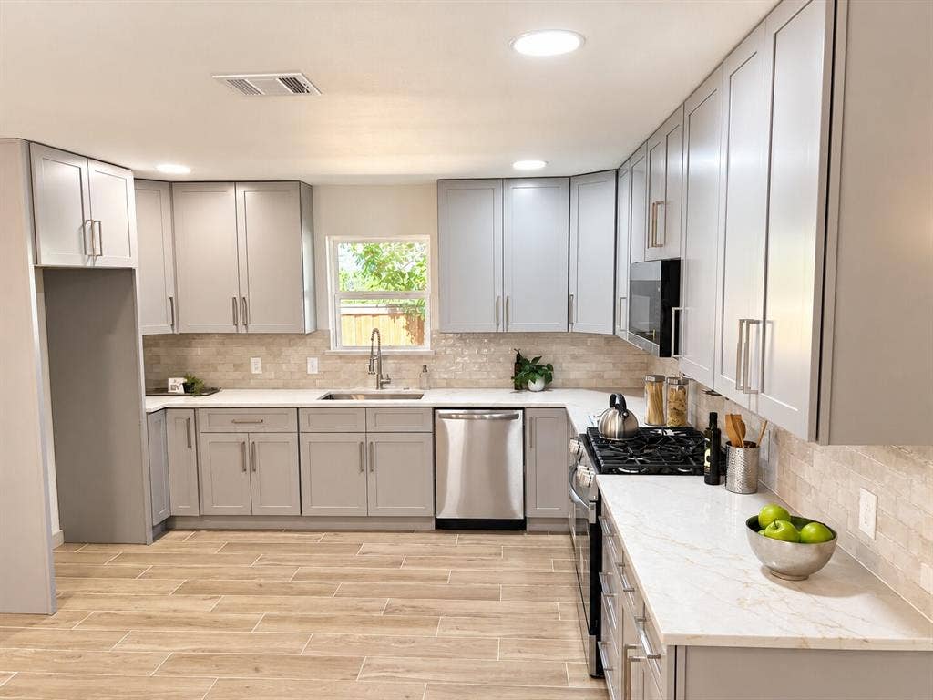 2551 Pinebluff Drive, Dallas, TX 75228 Kitchen featuring light grey cabinetry with brushed nickel hardware, white stone-finish countertops, subway-style tiled backsplash, stainless steel appliances, and wood-finish tile flooring