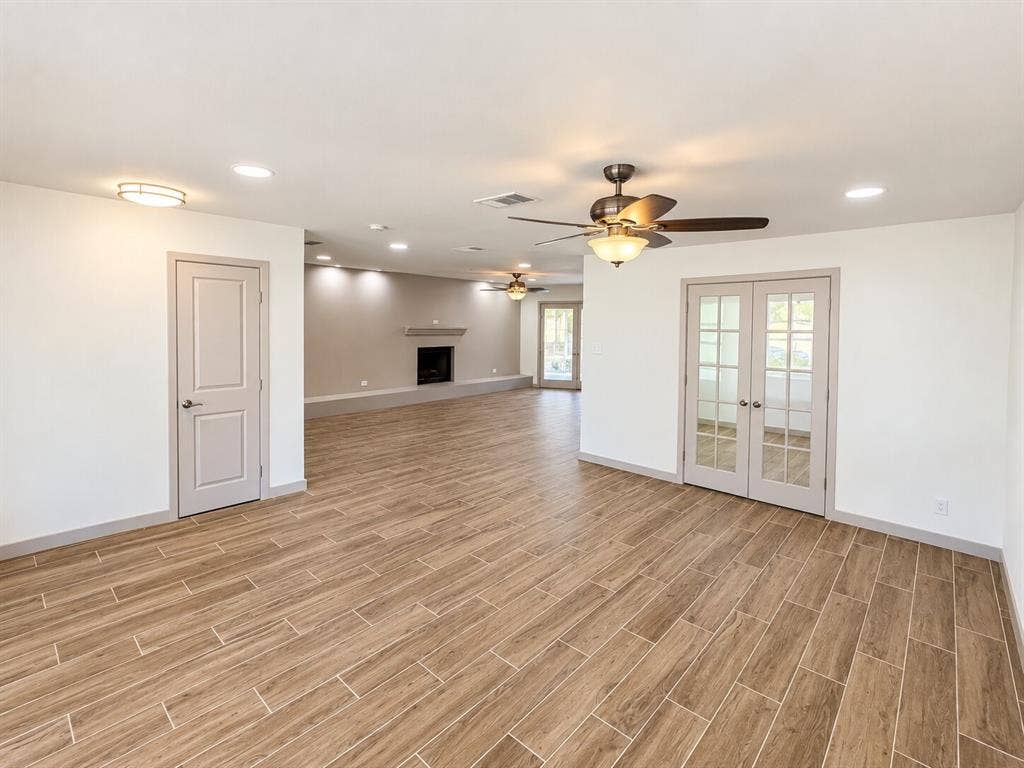 2551 Pinebluff Drive, Dallas, TX 75228 Open-concept interior featuring wood-finish flooring, recessed lighting, ceiling fans, a built-in fireplace with a raised hearth, and double French doors with glass panes