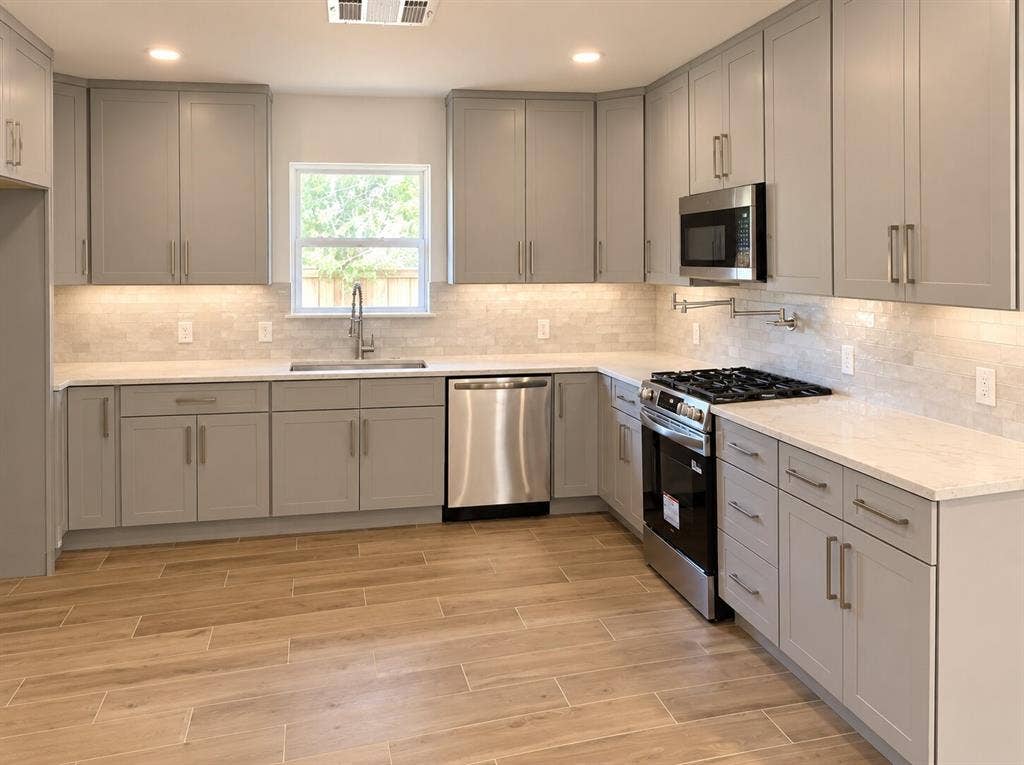 2551 Pinebluff Drive, Dallas, TX 75228 Kitchen featuring shaker-style cabinetry, light-toned stone-finish countertops, stainless steel appliances, a tile backsplash, and wood-finish flooring
