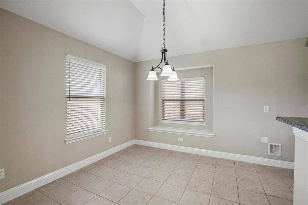Vaulted ceiling, ceramic tile flooring, built-in window seat, and three-light metal chandelier