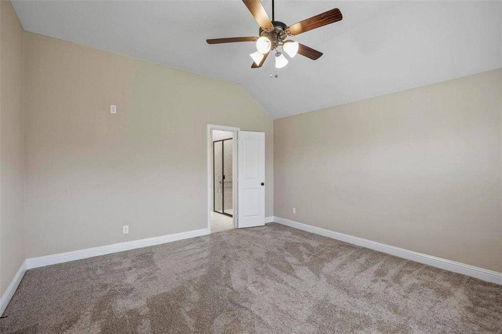 Vaulted ceiling, ceiling fan with light fixture, neutral wall color, and wall-to-wall carpeting