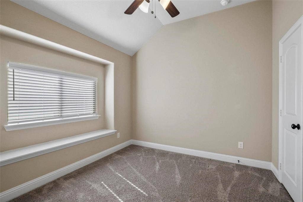 Vaulted ceiling with an overhead fan, built-in window seat, and wall-to-wall carpeting