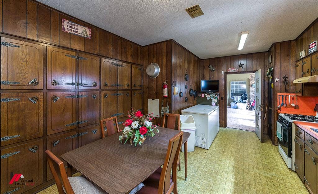 Floor-to-ceiling wood paneling, extensive built-in cabinetry with decorative hardware, and a gas range