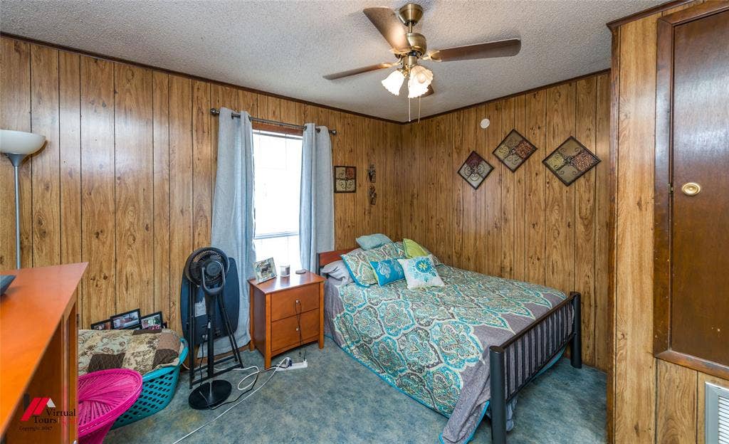 Wood-panelled wall treatments, ceiling fan with integrated lighting, and carpeted flooring