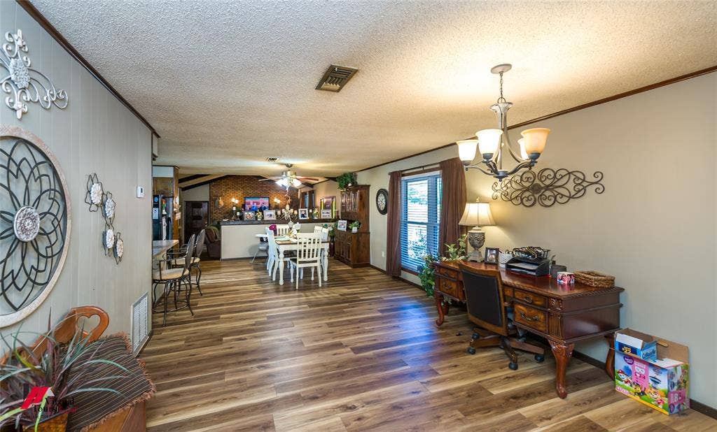 Open interior space featuring wood-finish flooring, a multi-arm chandelier with glass shades, and textured ceiling finish