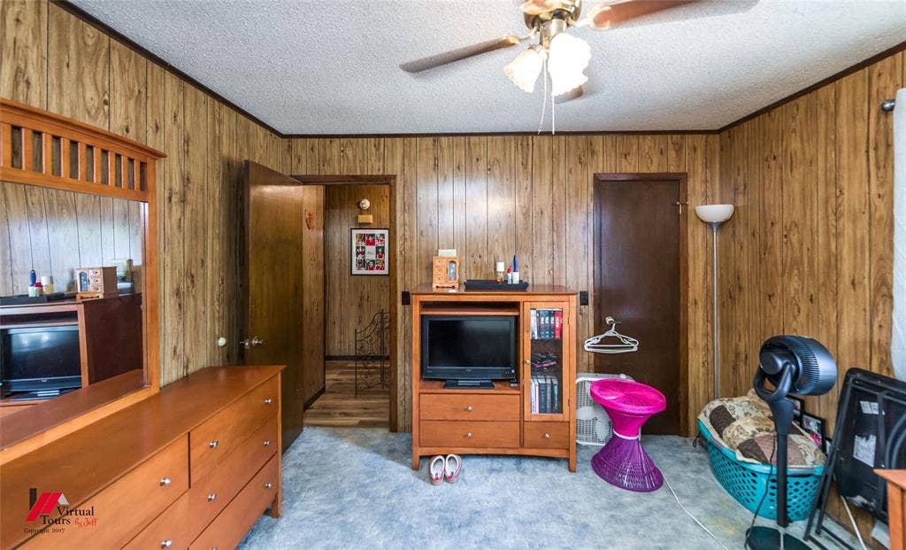 Wood-paneled wall treatments, ceiling-mounted light fixture with fan, and solid-core doors