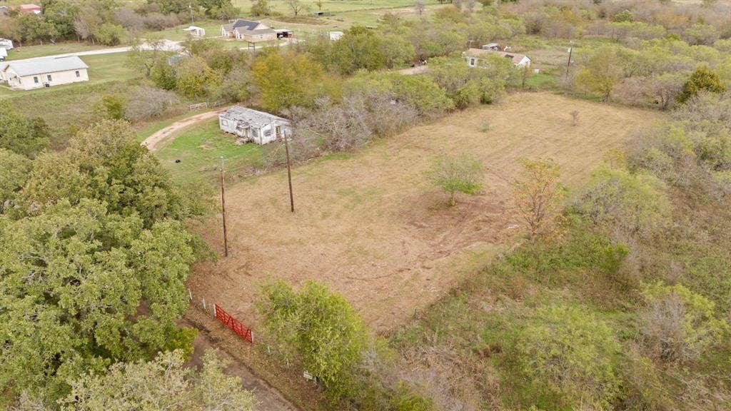 870 Wagoner Road, Waco, TX 76705 Expansive acreage featuring mature trees, a cleared grass expanse, and utility poles on-site